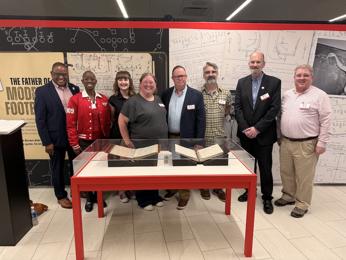 The whole team of librarians and library administrators who made the exhibit possible, standing with artifacts in theexhibits
